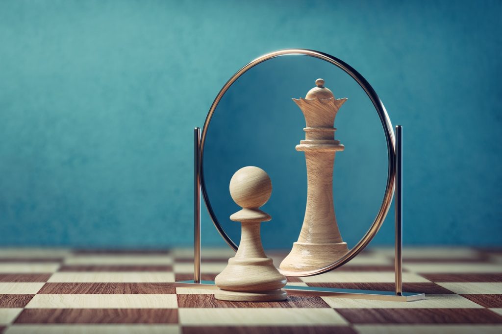 pawn chess piece looking in the mirror and seeing a queen